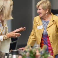 Two women talking while standing by table
